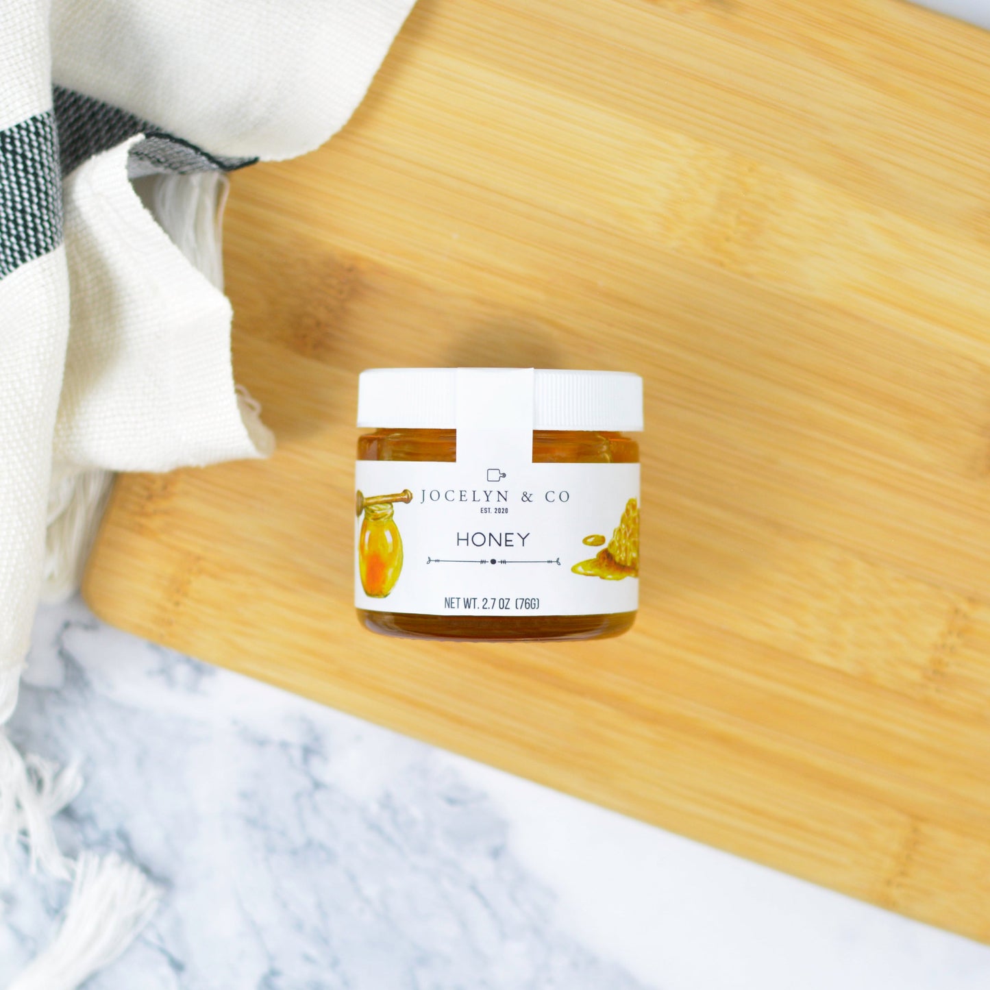 Jar of honey on a wooden cutting board with a marble background