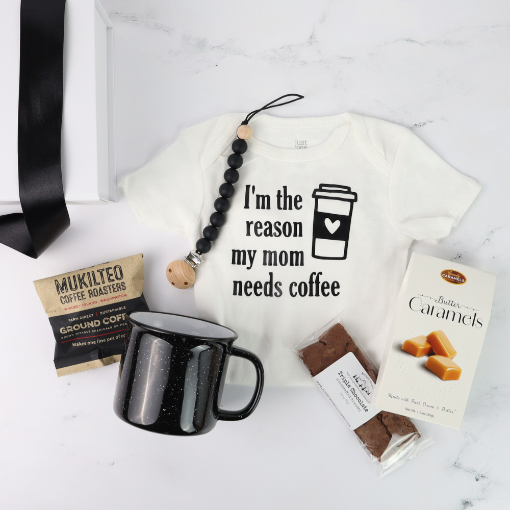 White t-shirt with 'I'm the reason my mom needs coffee' text, black mug, coffee package, and candy on a white background